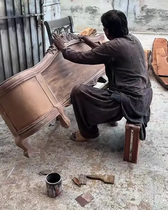 A carpenter fitting a carved bed frame